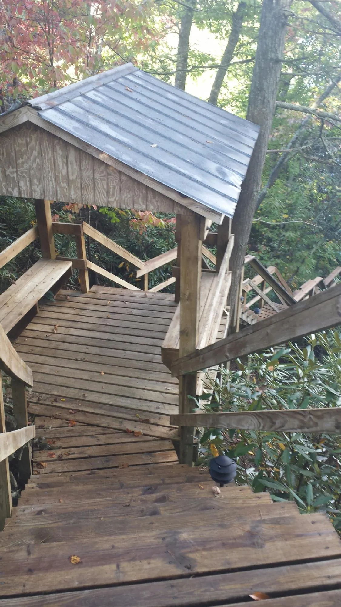 Metal roofed shelter over wooden steps on a wooded walkway — Skylight Repair & Installation work by our crew in Baxter Springs