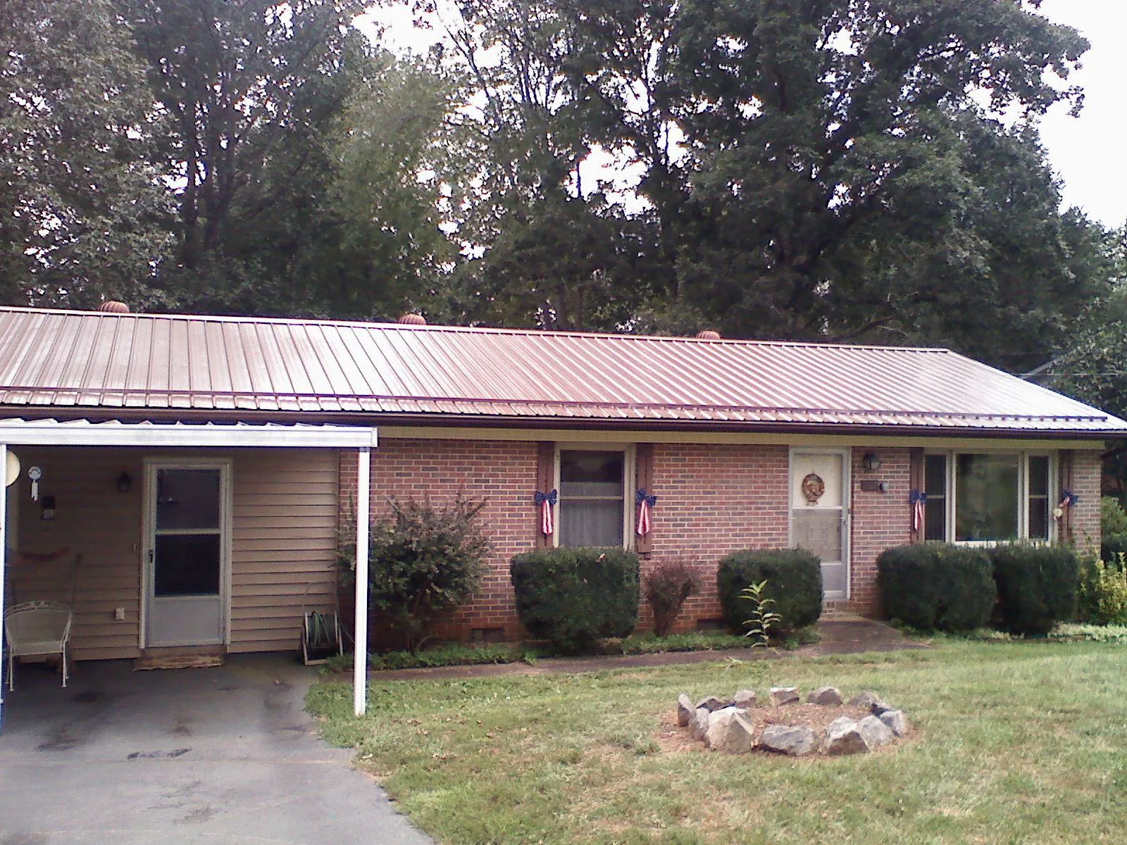 Bronze metal roof and carport on a brick ranch home — Roof Repair work by our crew in Baxter Springs